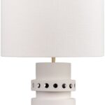 Tall off-white ceramic table lamp with geometric tiered base, circular cut-outs, and a white cylindrical shade.