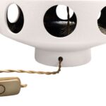 Tall off-white ceramic table lamp with geometric tiered base, circular cut-outs, and a white cylindrical shade.