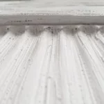 White textured wall art with vertical ribbed detailing and a semi-circular relief in a wooden frame.