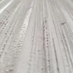 White textured wall art with vertical ribbed detailing and a semi-circular relief in a wooden frame.