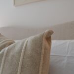 WAVE bed in natural weave fabric with curved upholstered headboard and round wooden legs in neutral modern bedroom.