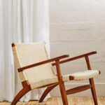 Natural rattan woven accent chair with solid mahogany wood frame, armrests, and mid-century boho styling for modern interior seating.