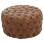Round tufted leather ottoman in vintage brown with button detailing and cushioned top, designed for classic and rustic interior seating.