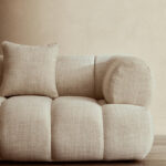 Cream linen curved three seater sofa with channel tufted detailing and rounded back design for modern luxury living room seating.