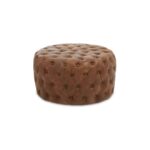 Round tufted leather ottoman in vintage brown with button detailing and cushioned top, designed for classic and rustic interior seating.